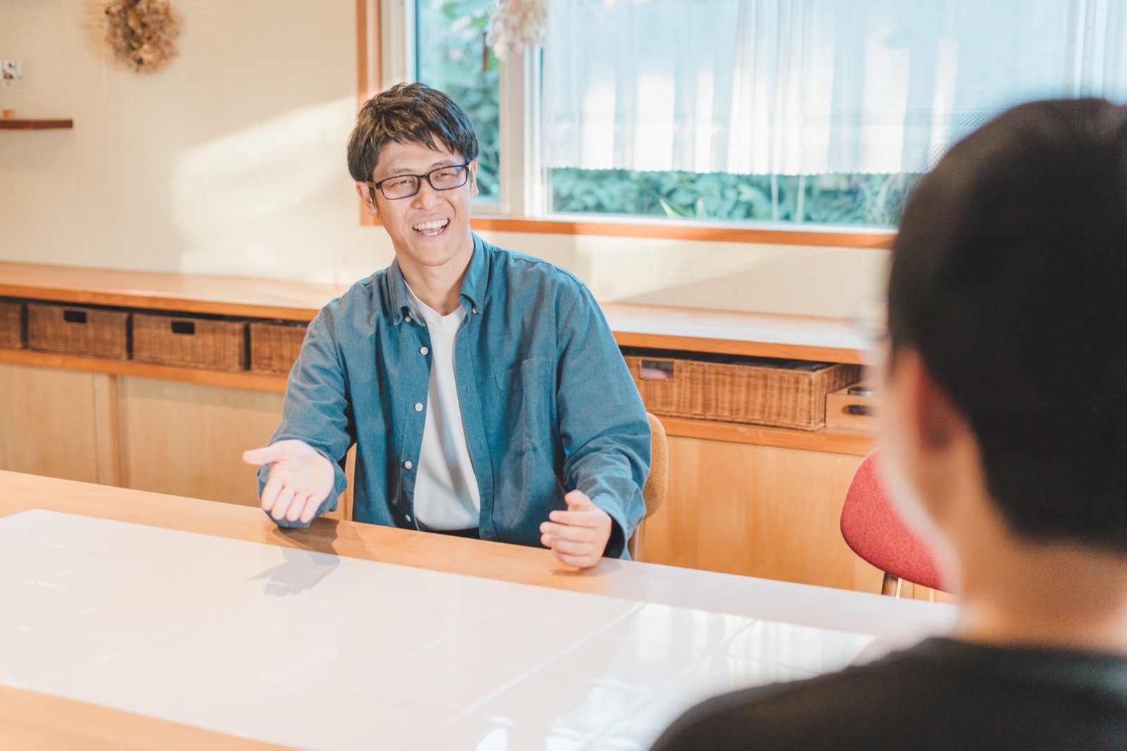 両手を広げて笑いながら商談するあべさん